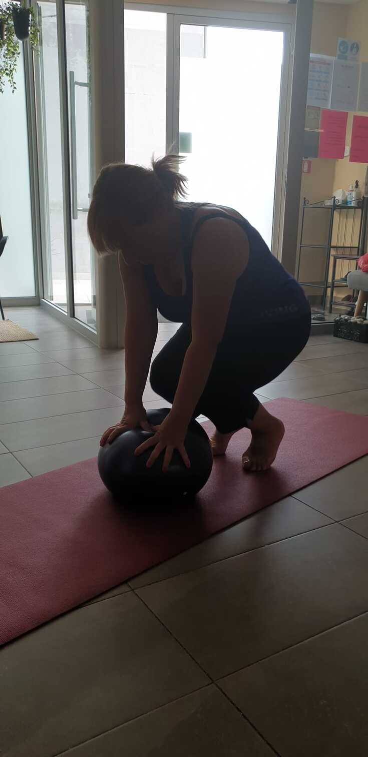 korektivne vježbe žene s loptom na crvenoj stunjači